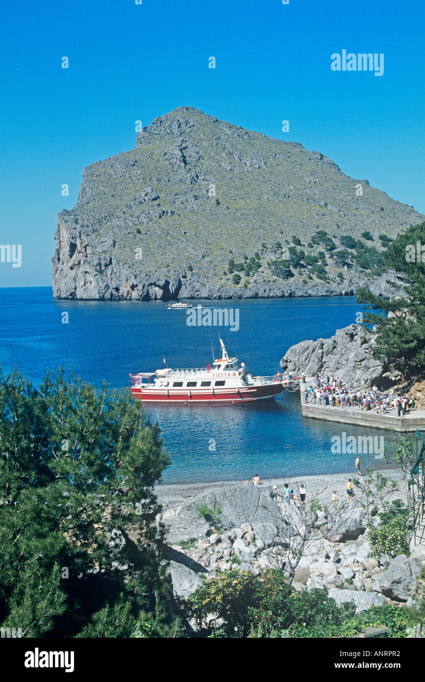 Touristen-Warteschlange auf einem Ausflugsschiff im Hafen von Sa Calobra mit seinen felsigen Landzunge ragen aus dem Meer, den Eingang zu der kleinen Bucht Unterschlupf zu beginnen Stockfoto