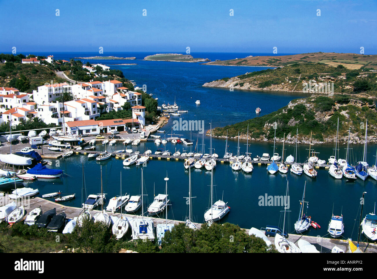 Angesehen von oben Sportboote und Yachten auf den Pontons in der Marina von weiß getünchten Villen mit roten Ziegeldächern an Port d Addaia auf der nördlichen Küste von Menorca übersehen gefesselt Stockfoto