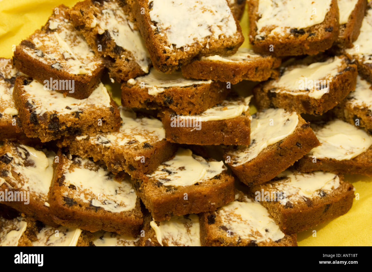 Teller voll mit in Scheiben geschnittenen und gebutterte Bara Brith [gesprenkelten Brot] traditionelle walisische reichen gemälzte Obst Laib Brot Stockfoto