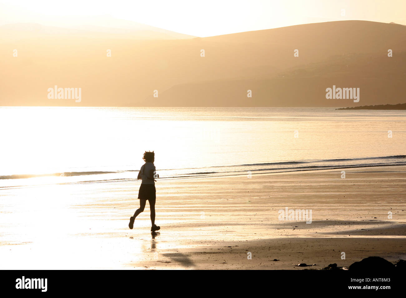 High-Key Schoß Frau Strand entlang joggen, im Morgengrauen Lleyn Halbinsel Wales UK Stockfoto