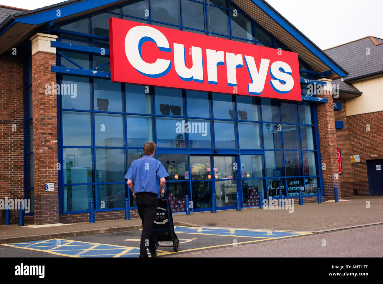Currys elektrischer Konsumgüter speichern Glas Außenfassade mit Mitarbeiter zu Fuß in Richtung des Shops. Aberystwyth Wales UK Stockfoto