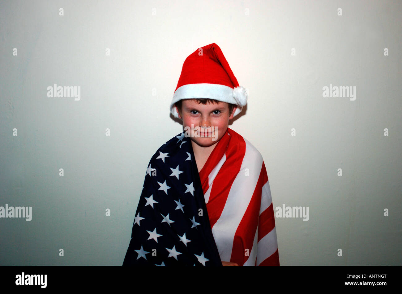 Ein 13 Jahre alter Junge, eingehüllt In den USA-Stars & Streifen kennzeichnen & trägt ein rotes & weiße Nikolausmütze. Stockfoto