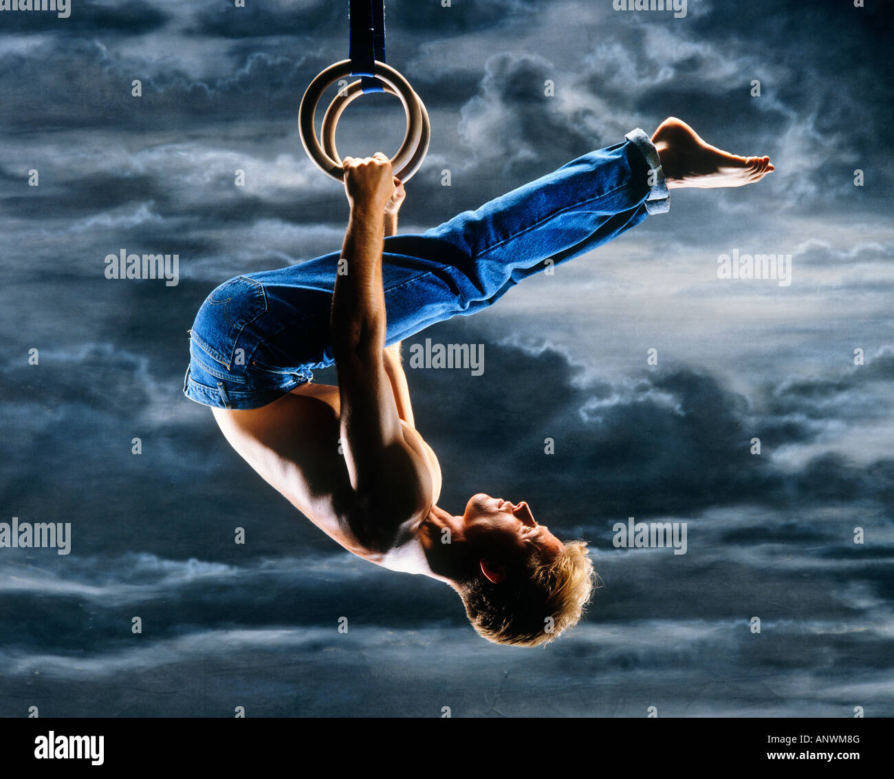 Mann in Jeans auf Gymnastik Reifen gegen Himmelshintergrund Stockfoto