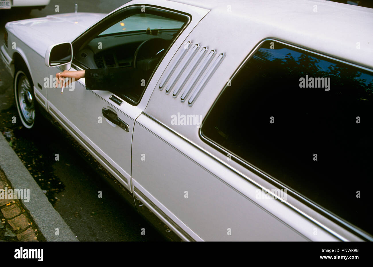 Limousinen Chauffeur hält seine Zigarette aus dem Autofenster Stockfoto