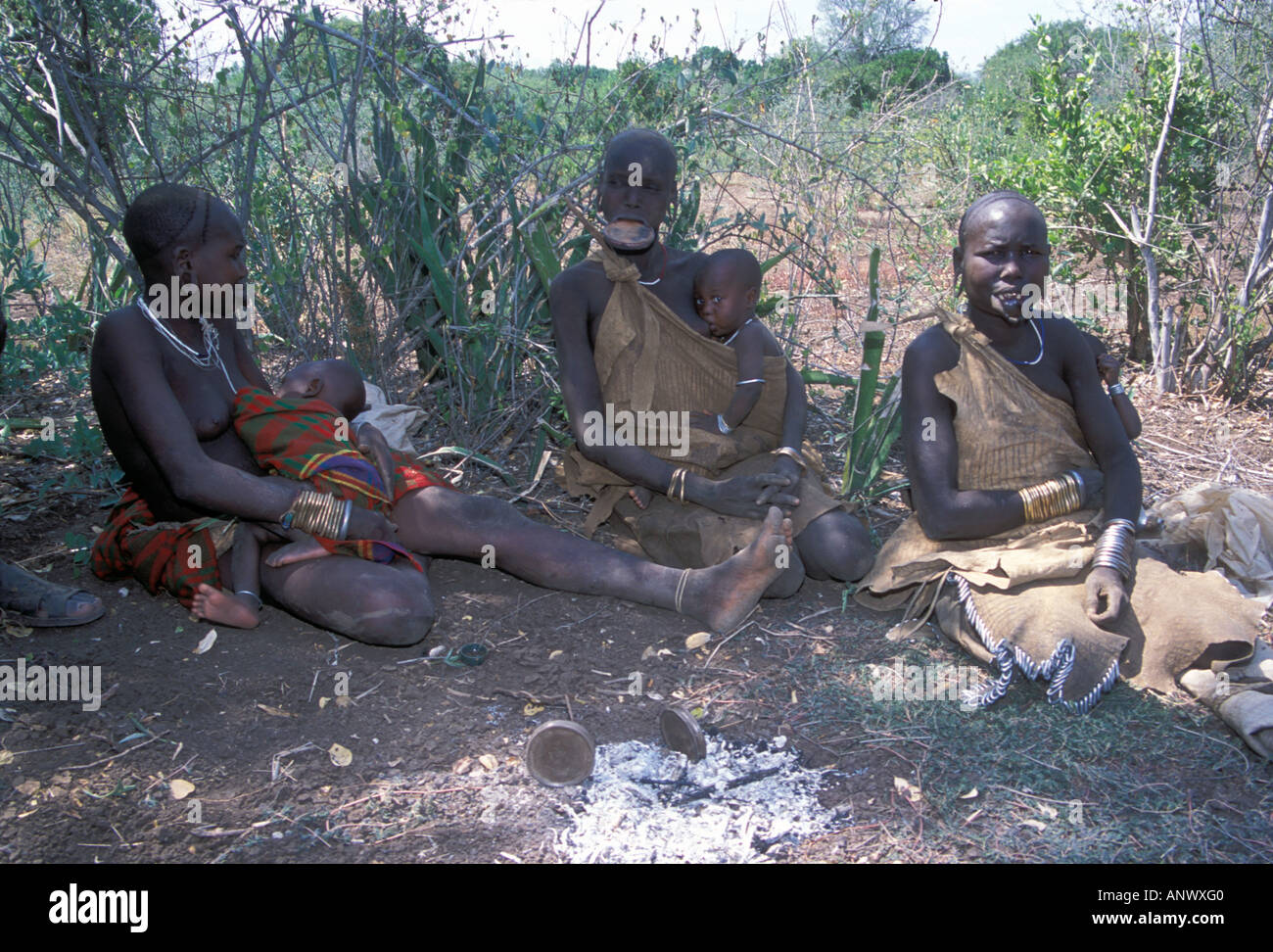 Drei Mursi-Frauen sitzen im Schatten an einem heißen Tag in Äthiopien, Afrika. (MR) Stockfoto