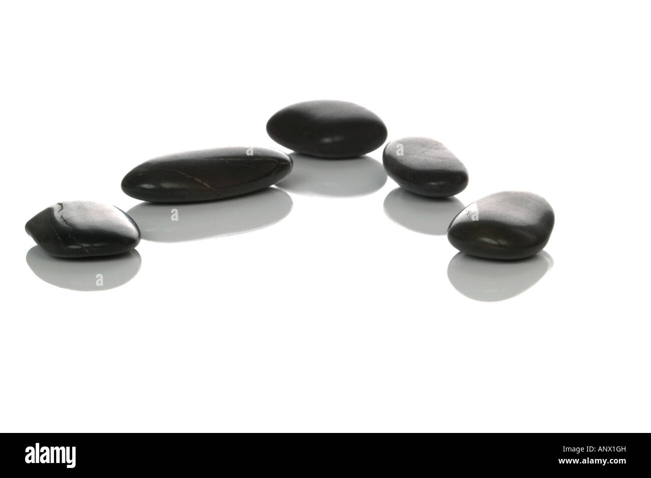 Fünf schwarze Kieselsteine mit Reflexionen auf weißem Hintergrund Stockfoto