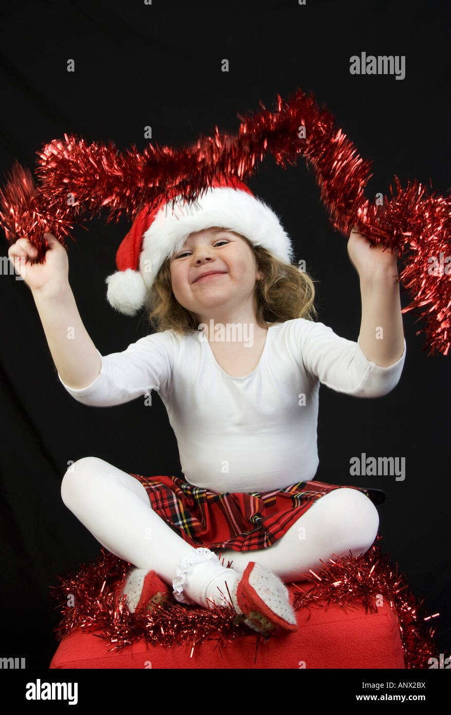 Weihnachtsmädchen mit Weihnachtsdekoration vor schwarzem Hintergrund Stockfoto