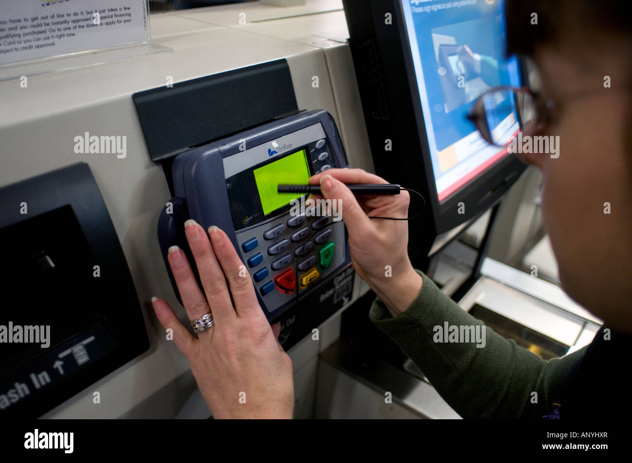 Frau schreibt ihre Unterschrift auf dem Display des Kreditkarten-Point of Sale-terminal in der Self-Checkout-Spur im Ikea in Seattle. Stockfoto