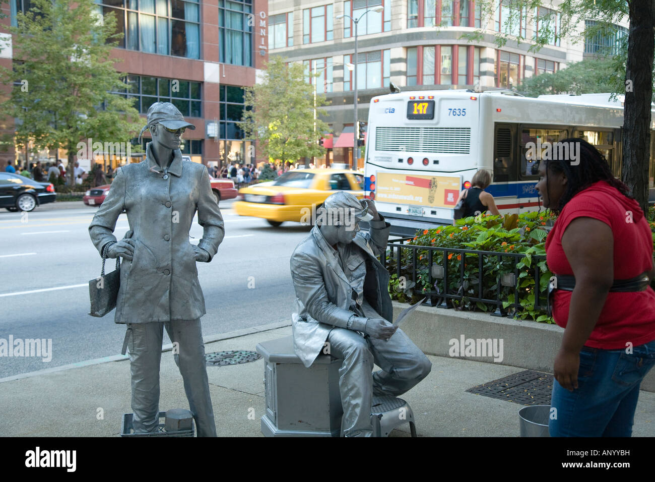 ILLINOIS-Chicago-Mann und Frau Straßenkünstler in Silber Make-up Gehsteig stehen und sitzen auf Bürgersteig Frau Geh nah ran Stockfoto