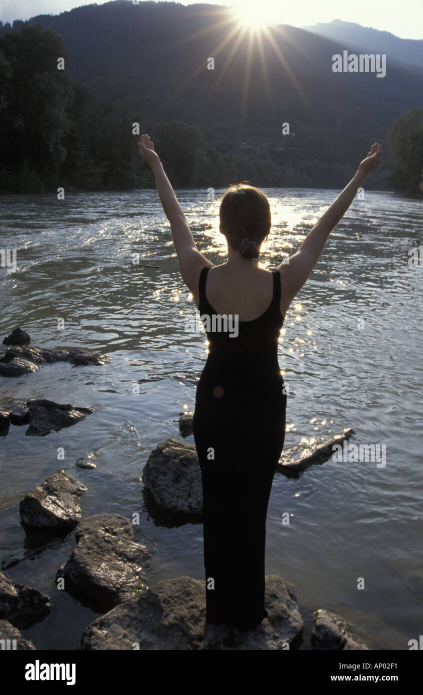 junge Frau am Flussufer, Sonne Stockfoto