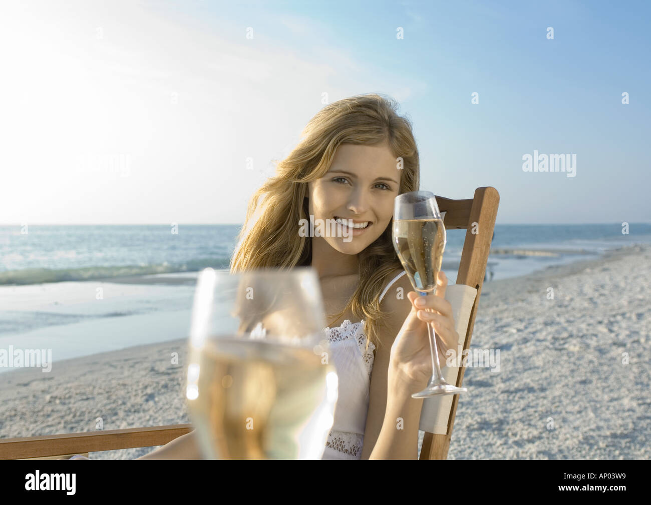 Junge Frau trinkt Champagner am Strand Stockfoto