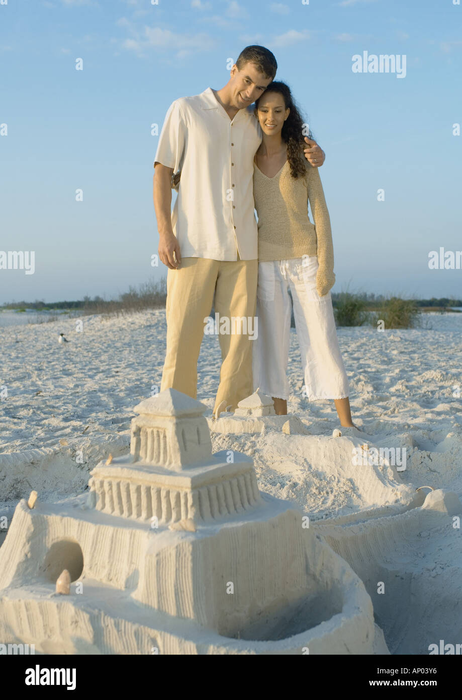 Paar steht am Strand mit Blick auf die Sandburg Stockfoto
