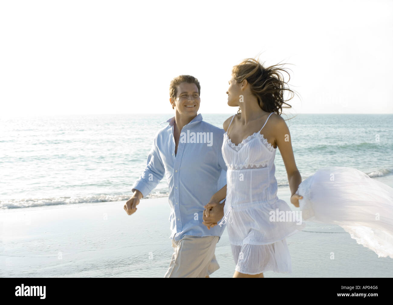 Paare, die am Strand, Lächeln einander an Stockfoto