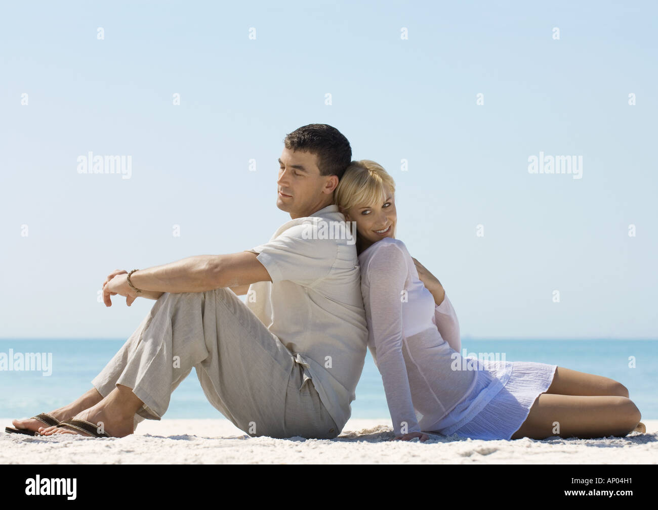 Paar am Strand sitzen Rücken an Rücken Stockfoto