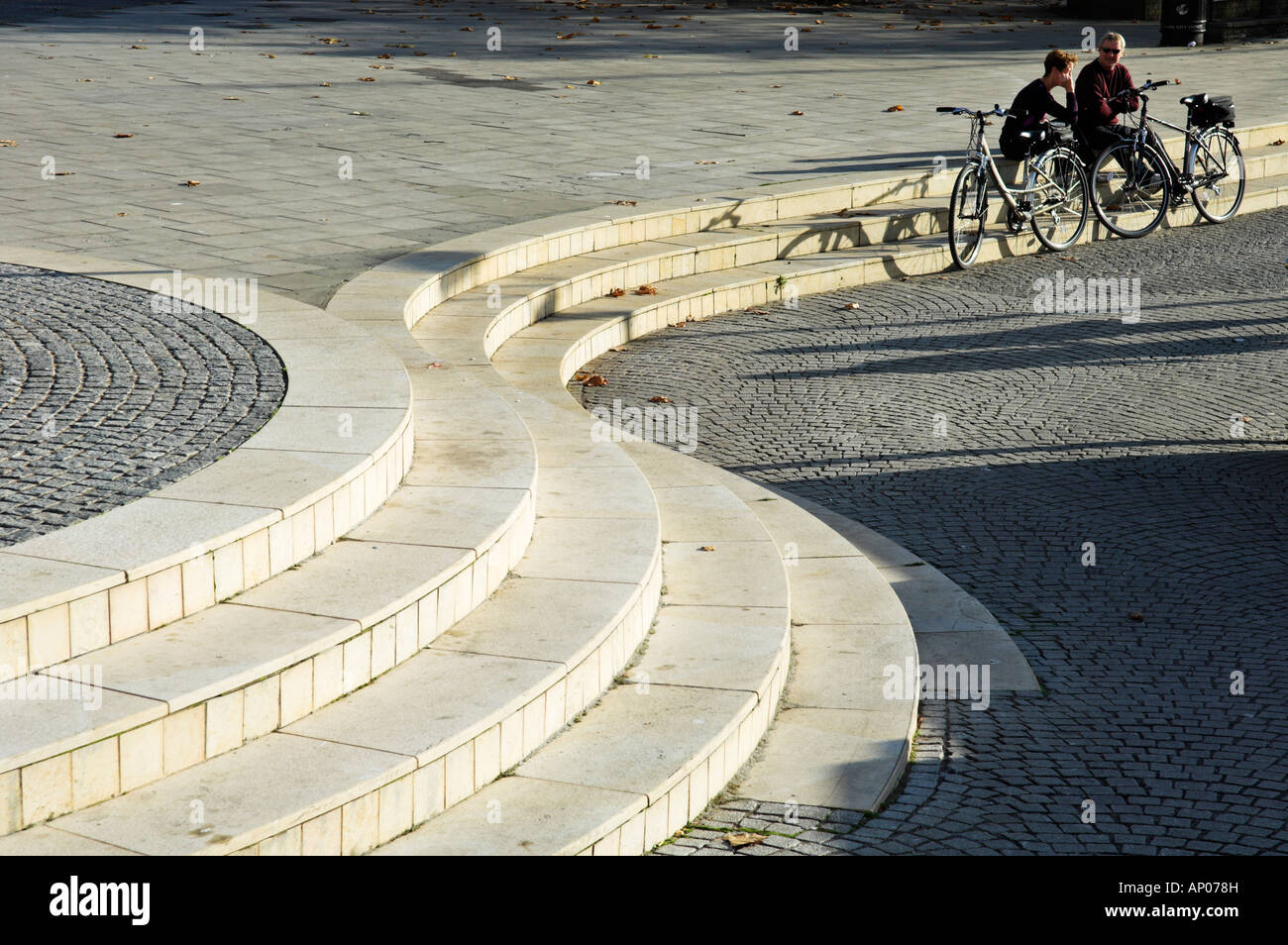 Menschen mit Fahrrädern sitzen auf geschwungenen Stufen Bristol City Centre England Stockfoto