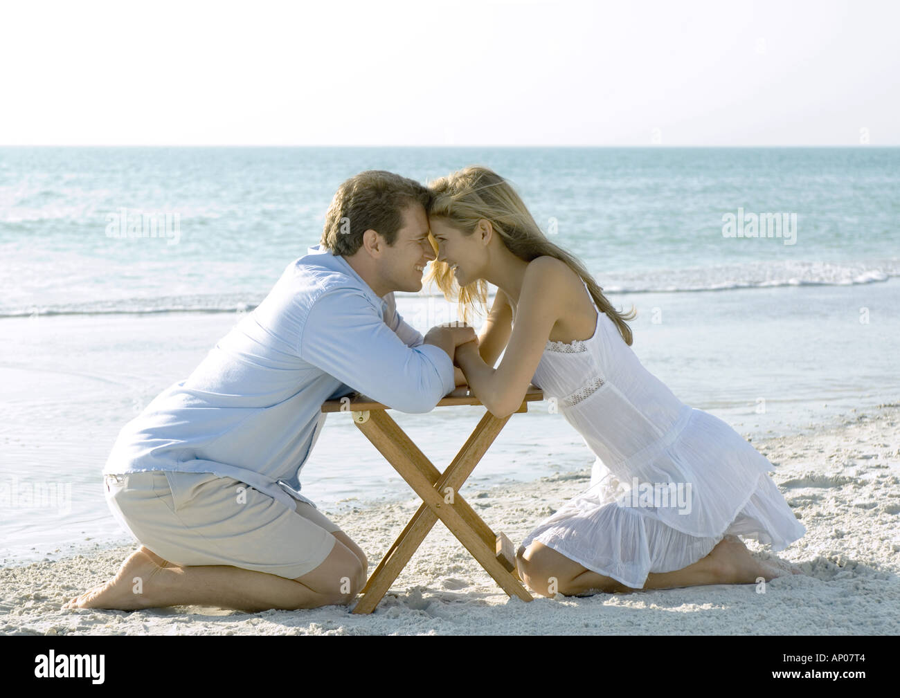 Paar am Strand, Kopf an Kopf kniend Stockfoto