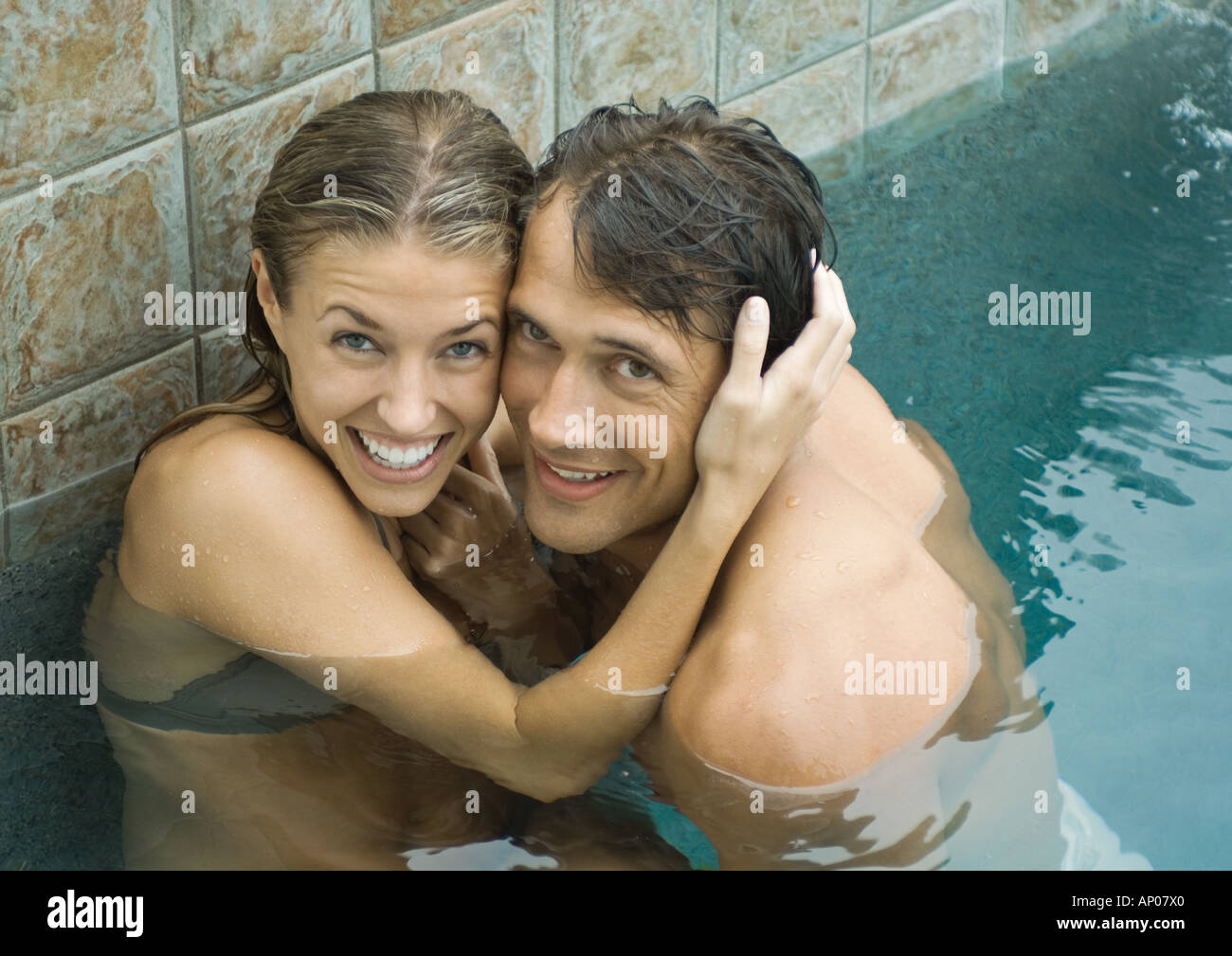 Paar im Schwimmbad, Wange an Wange, lächelnd in die Kamera Stockfoto