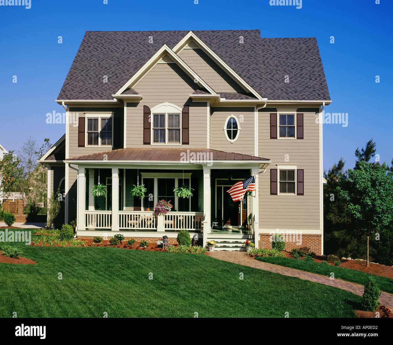 Frontansicht des einen großen braunen zweistöckiges Haus mit weißem trim und eine große Veranda und Garten Stockfoto