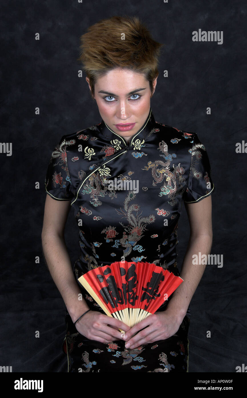 Junge Frau kniet in einem chinesischen Kleid mit einer roten Fan Stockfoto