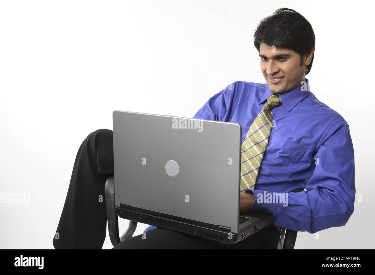 ANG200147 Executive lächelnd mit ungeraden Körperhaltung entspannt halten Laptop auf Schoß auf Stuhl sitzend Stockfoto