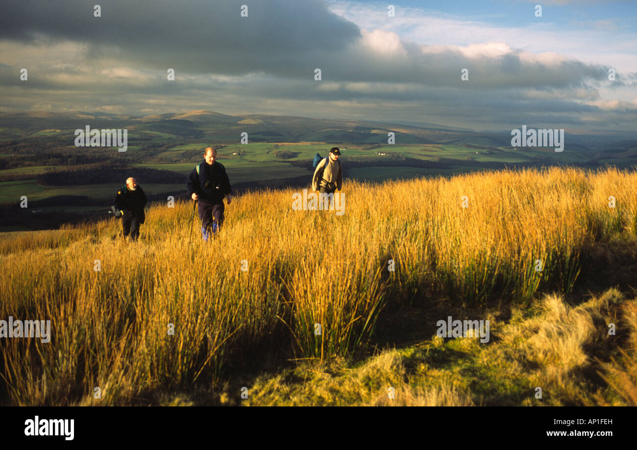 Winter-Landschaft Morgensonne scheint auf drei Wanderer zu Fuß in die Durisdeer Hills Scotland UK Stockfoto