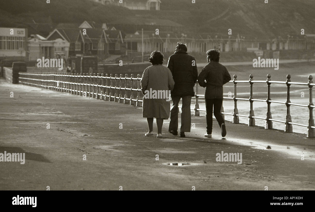 Rückansicht von drei Menschen, die zu Fuß am Meer entlang North Bay in Scarborough. Stockfoto