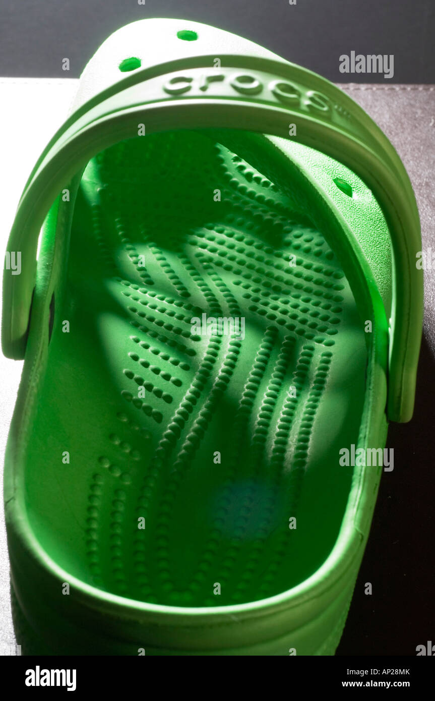 Ein helles Grün mit Licht, das durch das Muster der Bohrungen in das Oberteil Crocs verstopfen Stockfoto
