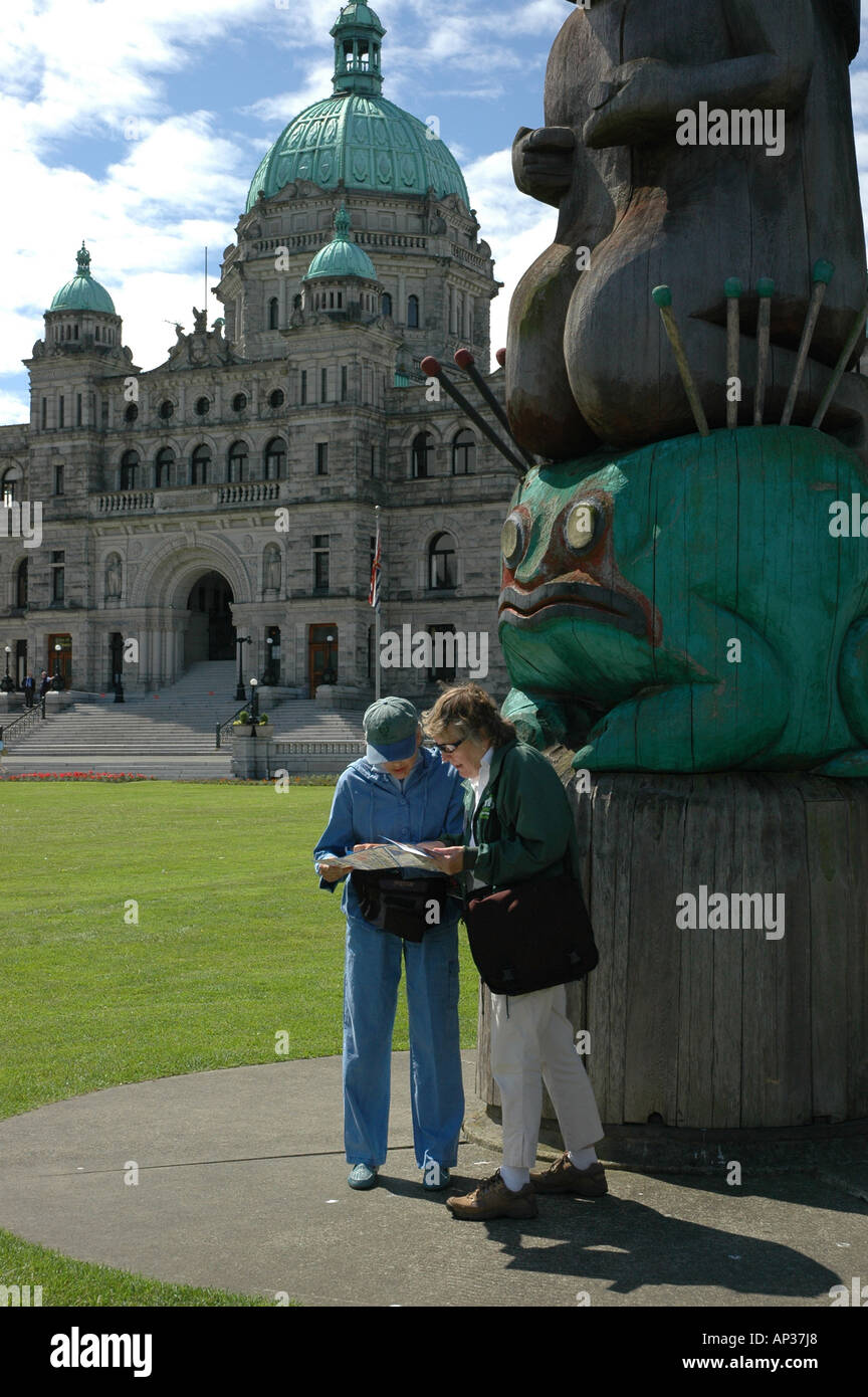 Touristen schauen Sie sich die Karte vor Totempfahl und The British Columbia Legislative Building, Victoria British Columbia Stockfoto
