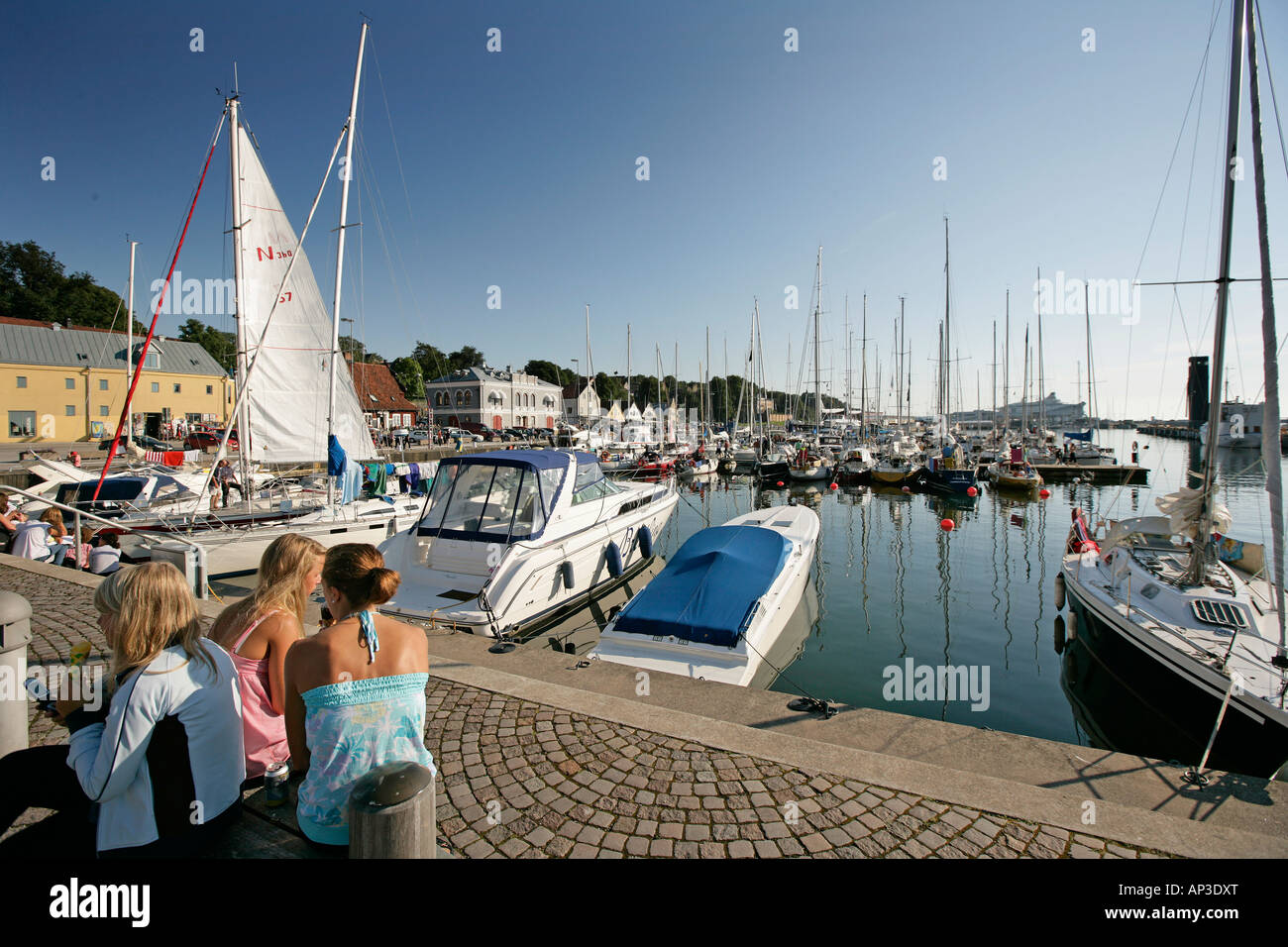 Drei Mädchen sitzen durch den Hafen von Visby, Gotland, Schweden Stockfoto