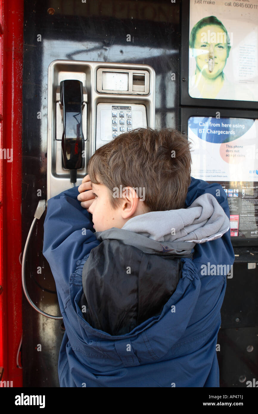 Jungen im Alter von 11 Jahren alten unglücklich traurig besorgt Ausreißer innerhalb einer öffentlichen Telefonanruf box gestellt nach Modell Stockfoto