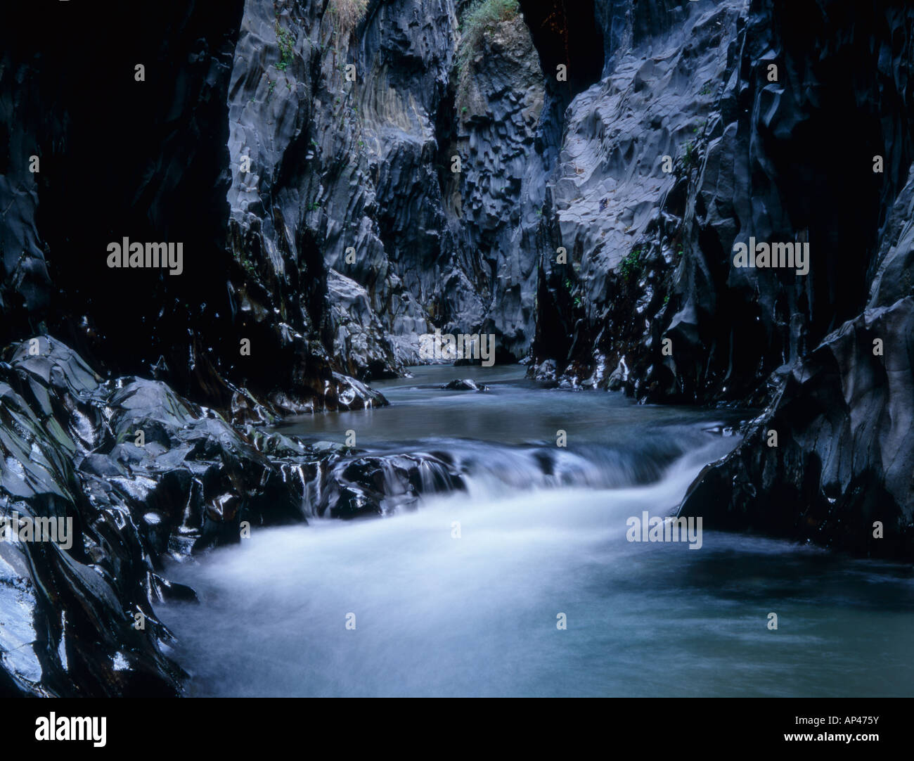 Ein Fluss fließt durch die vulkanischen Felsen der Alcantara Schlucht Alcantara River Park, Sizilien, Italien Stockfoto