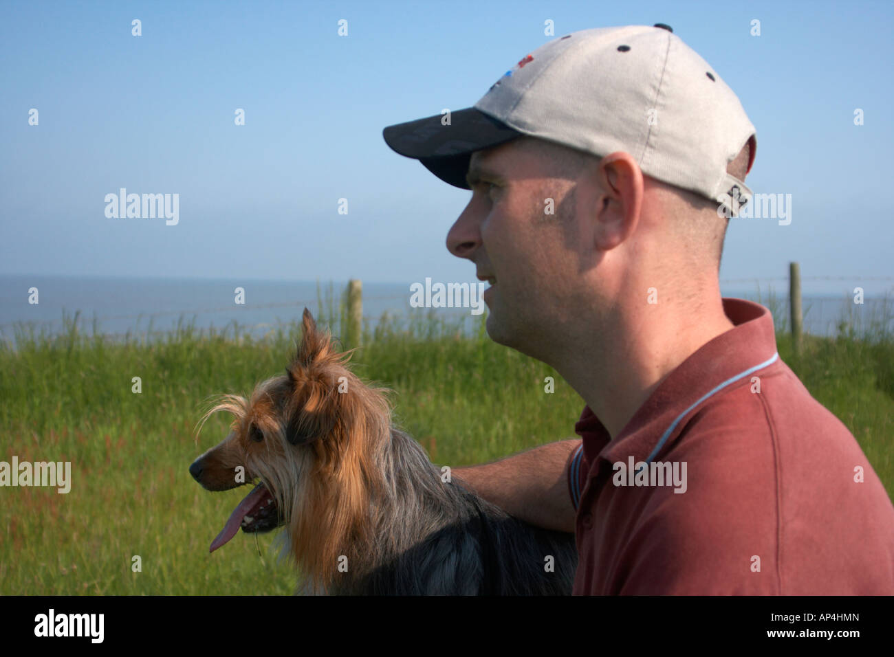 Ein Mann und ein Hund auf einer Klippe mit Blick auf das Meer Stockfoto