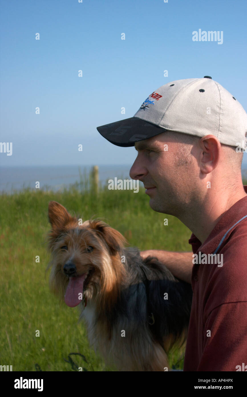 Ein Mann und ein Hund auf einer Klippe mit Blick auf das Meer Stockfoto