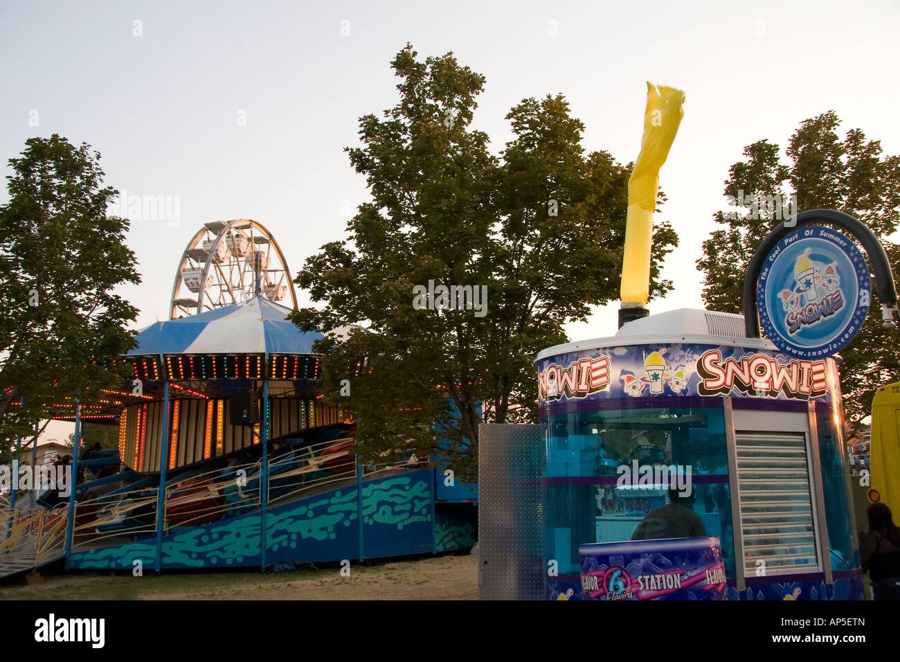 Hier sind drei gemeinsamen Sehenswürdigkeiten bei einer State Fair oder Vergnügungspark: ein Riesenrad, eine "Spinnerei" Park Fahrt & eine Snowcone stehen. Stockfoto