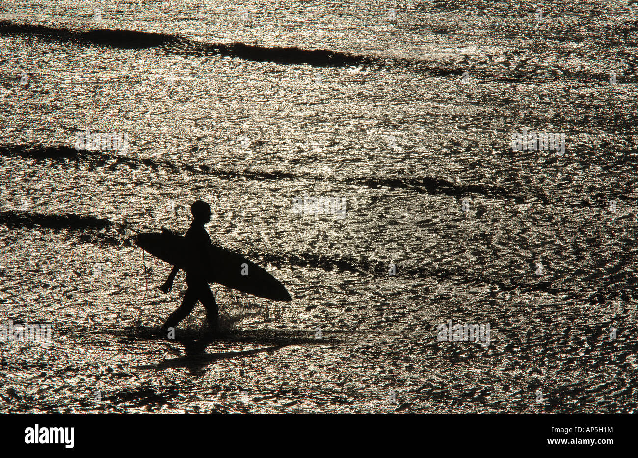 Eine Surfer ist Silhouette zu Fuß in die Wellen im Saunton Sands Beach in North Devon UK gesehen. Stockfoto