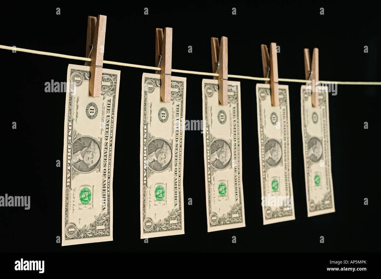 US-Dollar Hung Out auf einer Wäscheleine vor schwarzem Hintergrund Stockfoto