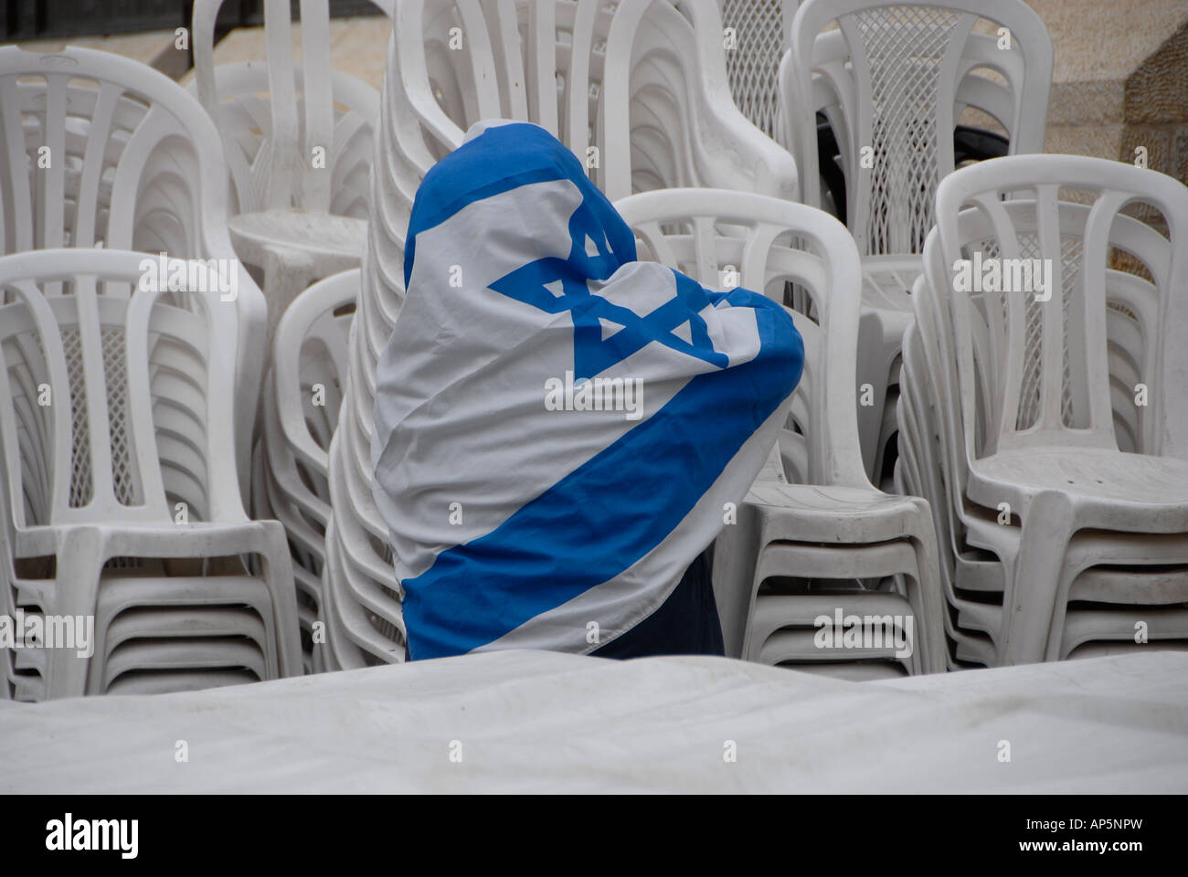 Israelischer Mann mit der israelischen Flagge, die weißen Plastikstühle für eine Zeremonie, während der Tag der Unabhängigkeit Israels gewickelt Stockfoto