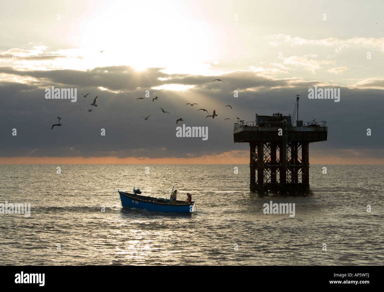 Angelboot/Fischerboot in der Morgendämmerung auf der Küste von Suffolk arbeiten runden Sizewell A Kernkraftwerk Kühlung Wasserauslauf mit Möwen kreisen Stockfoto