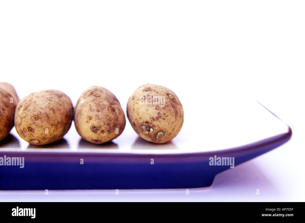 Eine Reihe von frischen jungen Kartoffeln, aufgereiht auf einer rechteckigen Platte sauberen, weißen Hintergrund Stockfoto