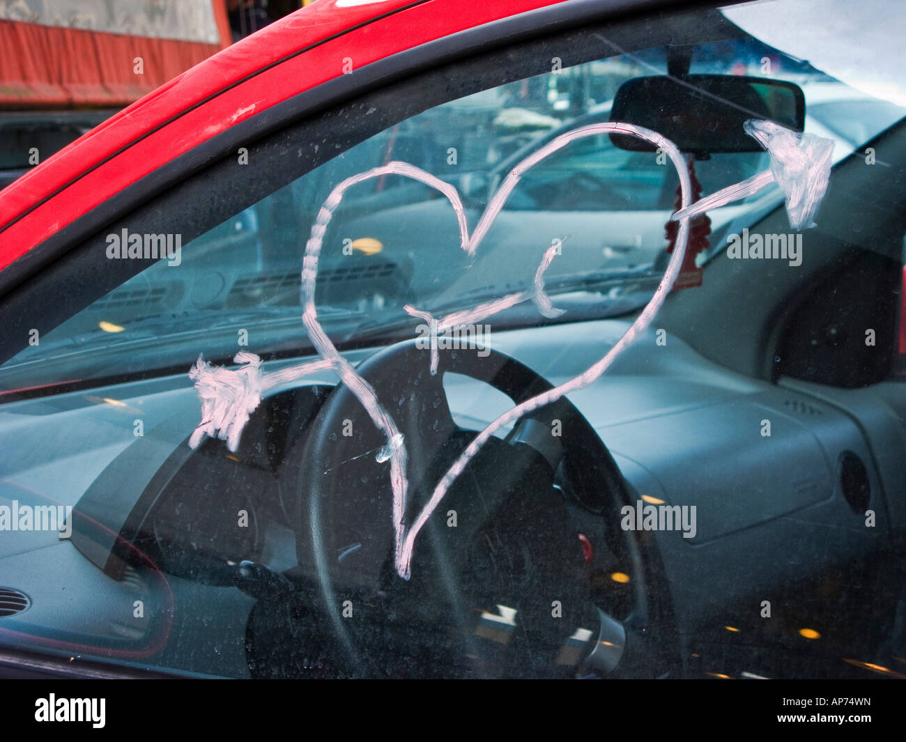 Rotes Herz und Amor Pfeil mit Lippenstift auf Autofenster
