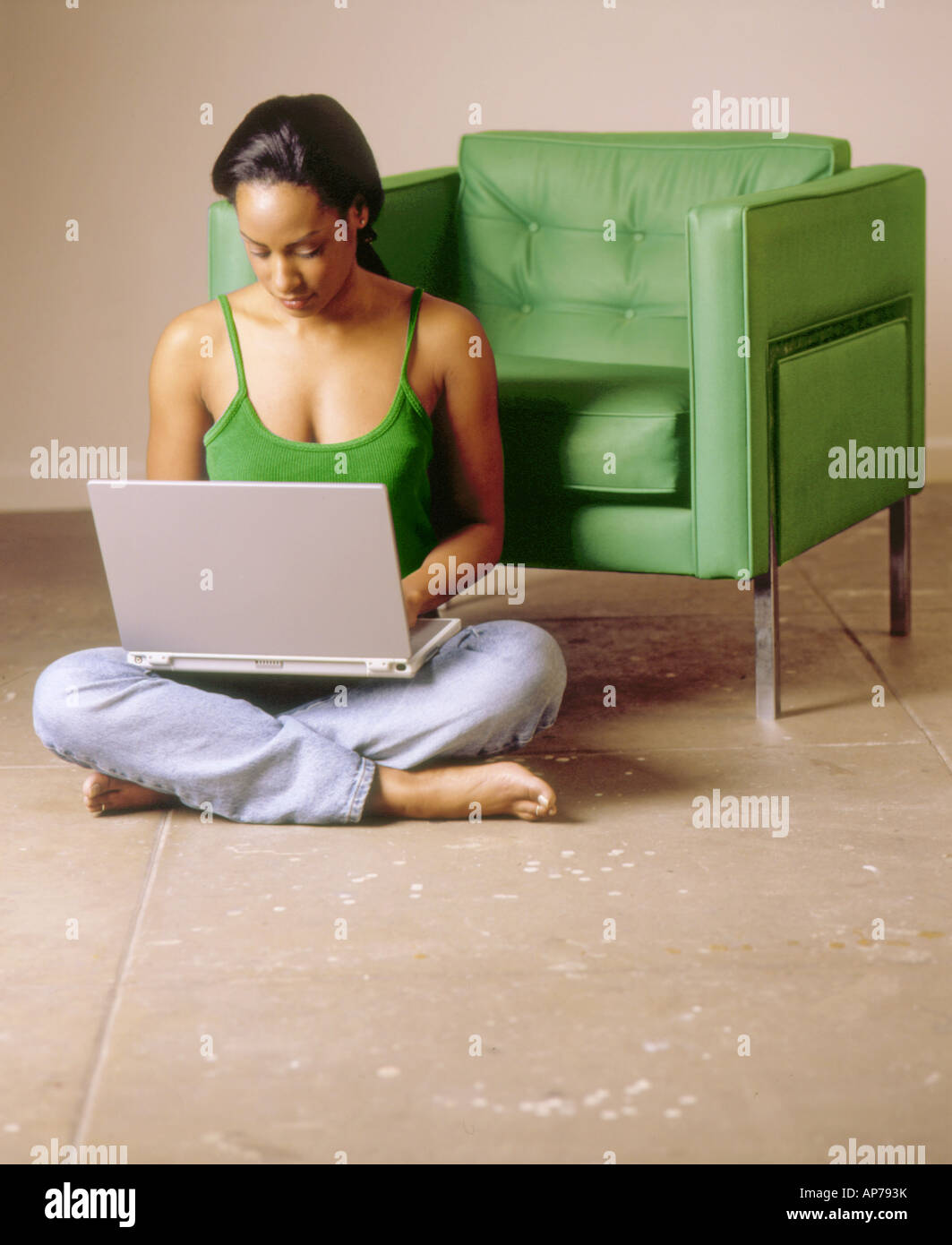Afrikanische amerikanische schwarze Frau sitzt mit grünen moderner Stuhl im Zimmer Erdgeschoss mit Laptop arbeiten oder online-shopping Stockfoto
