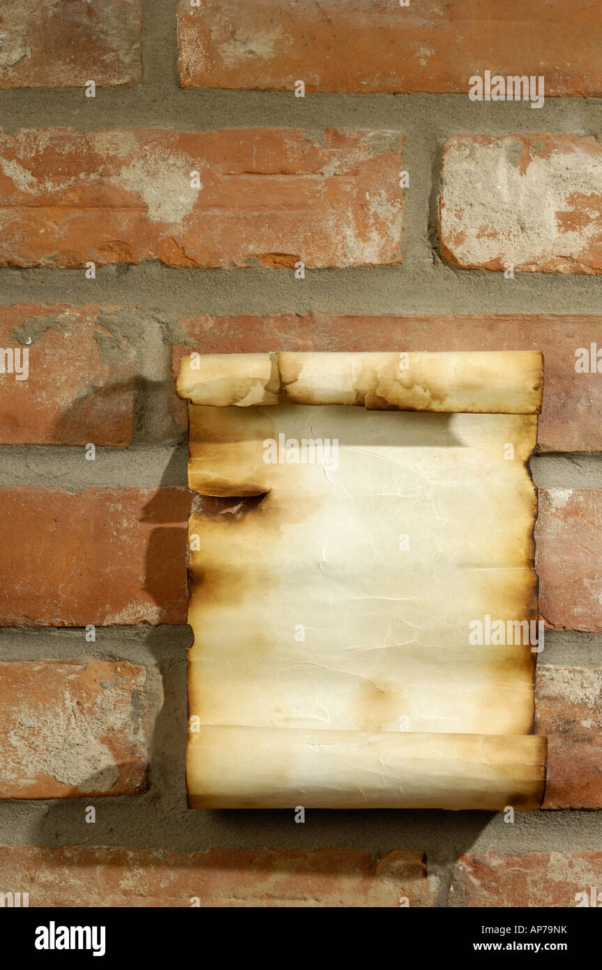 Altes Pergament mit verbrannten Ränder auf Ziegelmauer Stockfoto