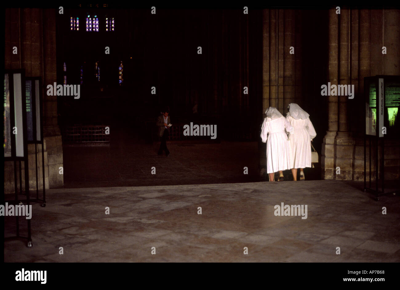zwei Nonnen In Paris tragen weiße Outfits zu Fuß entfernt von der Kamera in Kirche Stockfoto