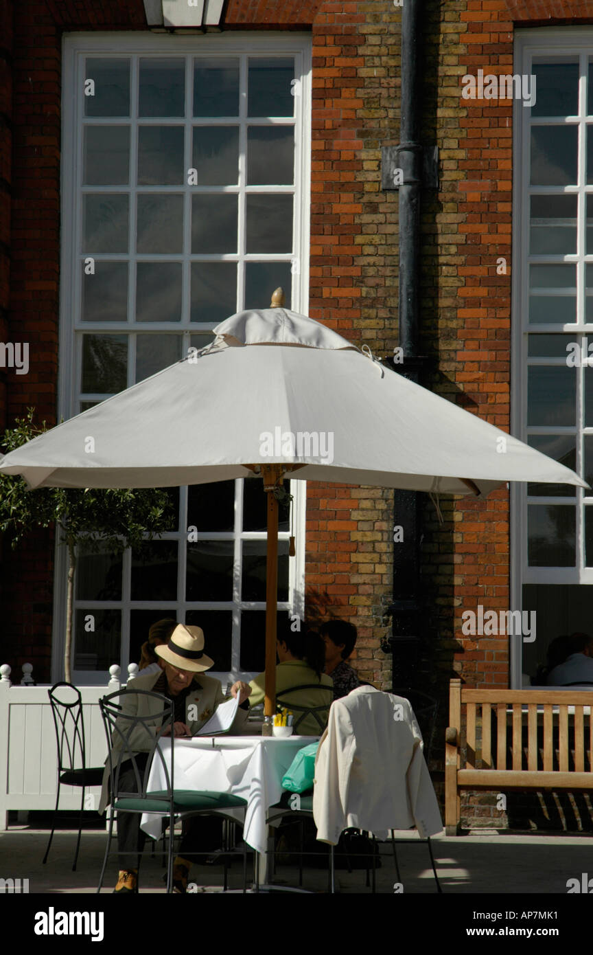 Elegant gekleidete Mann sitzt vor der Orangerie-Restaurant im Kensington Palace Gardens London UK Stockfoto