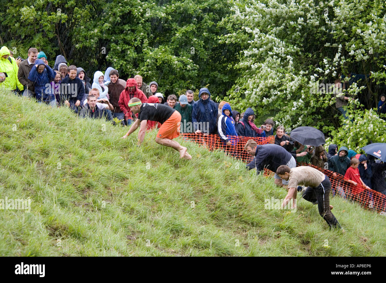 Die Mens bergauf Rennen im Regen auf dem Coopers Hill Cheese Rolling-Event auf der Cotswolds bei Brockworth, Gloucestershire Stockfoto