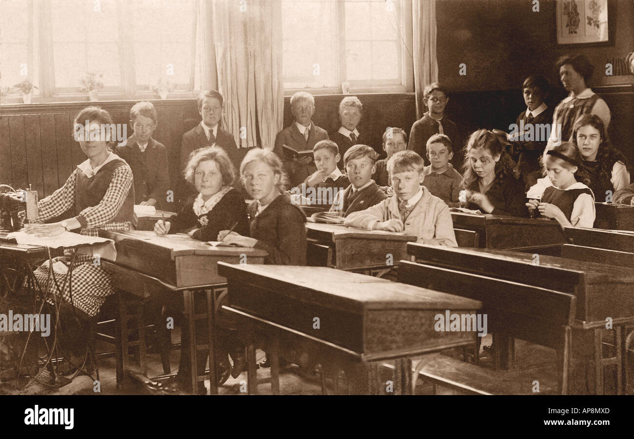 Kinder im Jugendalter in einem Klassenzimmer an der Grundschule, mit einem Lehrer, der eine Nähmaschine benutzt, Handarbeitsstunde, Cambridge, England, Großbritannien - um 1918 Stockfoto