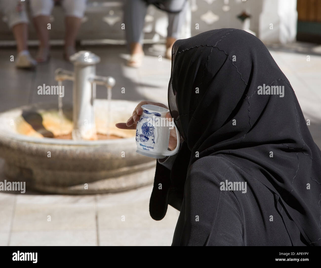 Muslimische Frau trägt schwarze aus Spa Mineralwasser trinken schneiden Pramen Svoboda Frühling Karlovy Vary Tschechien Stockfoto