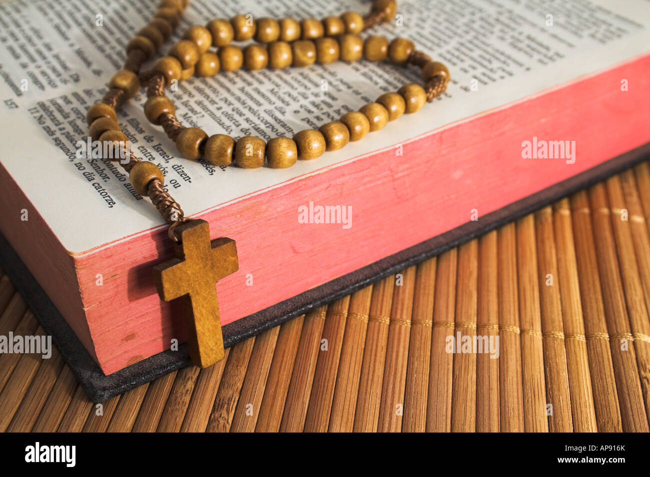 Aufgeschlagene Bibel mit Rosenkranz auf dem Stroh Tisch Stockfoto