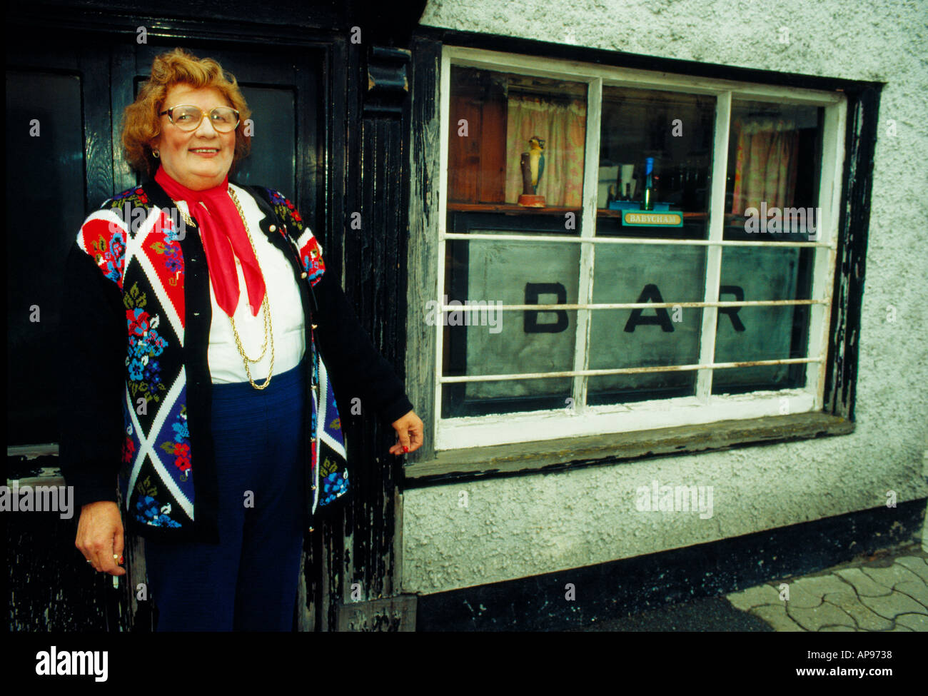 Frau im bunten Cardigan und rotem Schal vor einer Bar in Hay on Wye UK Stockfoto