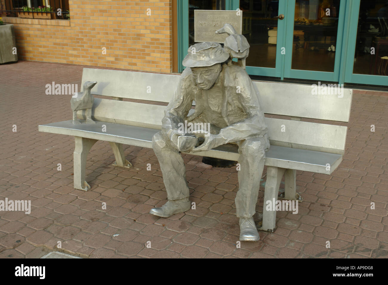 AJD50929, Bend, OR, Oregon, Innenstadt, Statue eines Mannes sitzen auf einer Bank mit zwei Enten Stockfoto